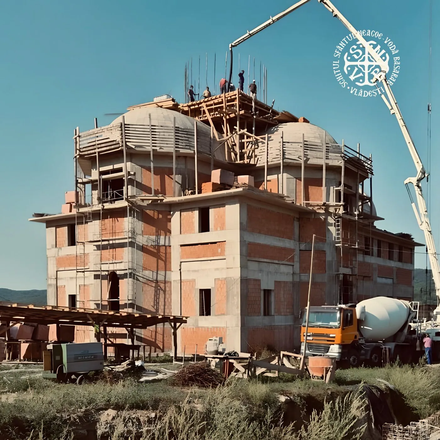 Biserica în construcție, cu turla în schele și pompa de beton la lucru